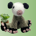 crocheted Opossum plushie with pink toe details on a green background