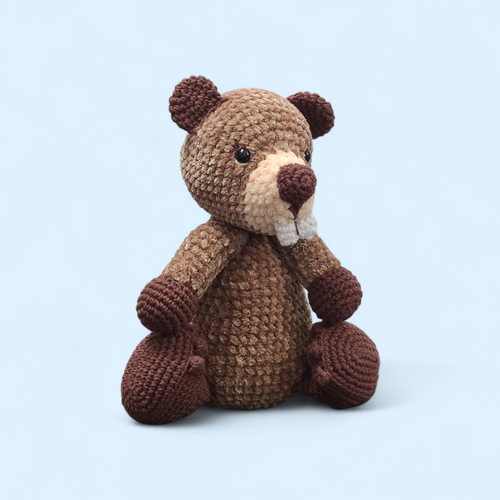Crocheted beaver with buck teeth and brown body on a light blue background