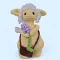 Crocheted yellow Forager creature holding a bundle of lavender on a light blue background