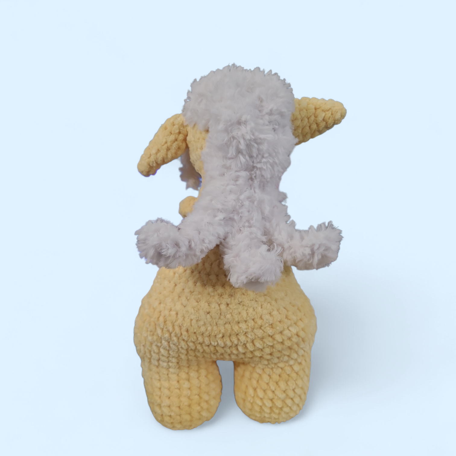 Crocheted yellow Forager creature  on a light blue background