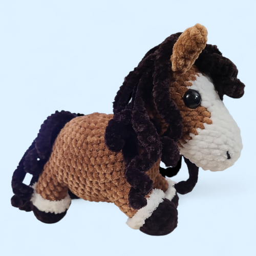 Crocheted horse toy with brown, black, and white colors on a light blue background