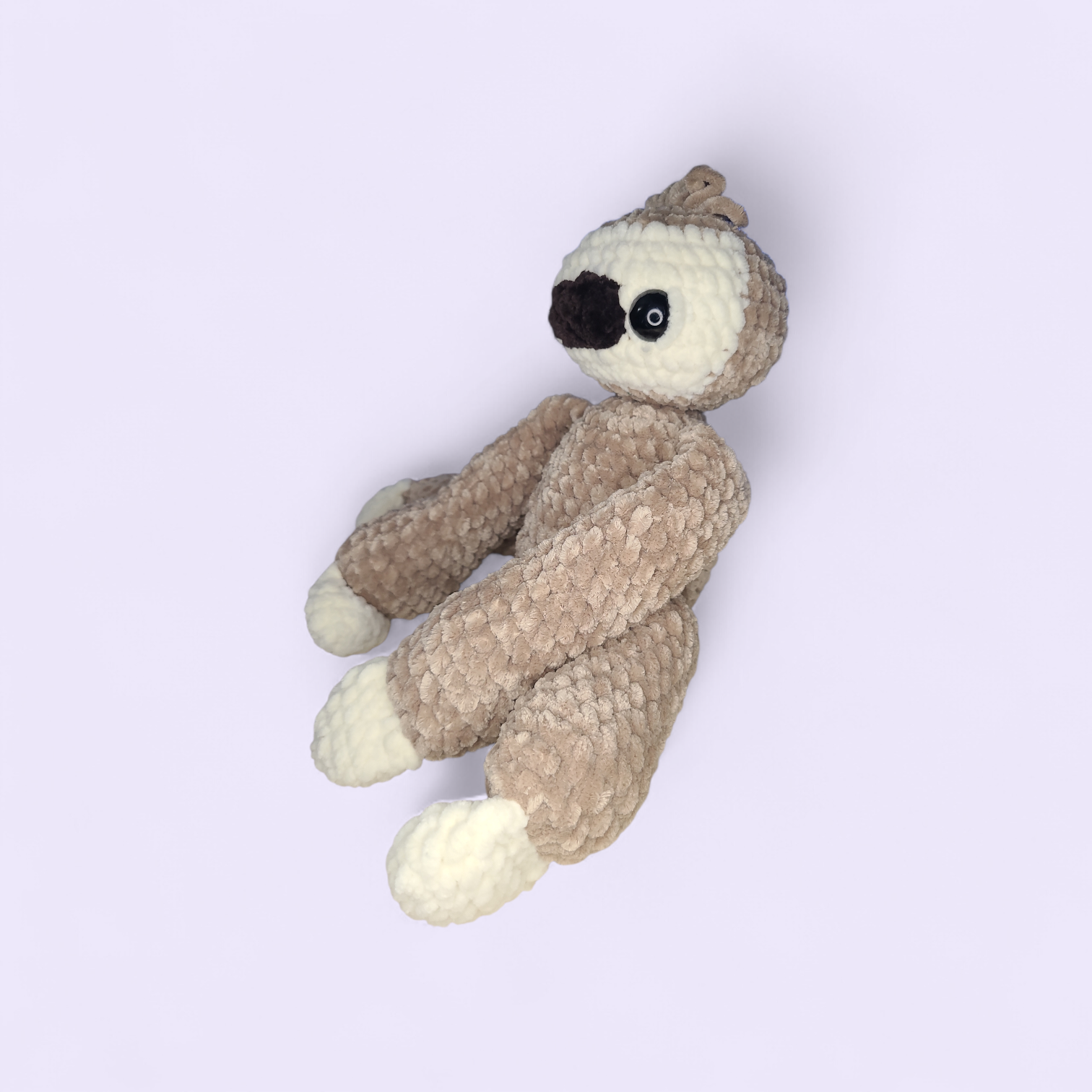 Crocheted sloth on a light purple background