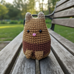 Crocheted Dumpling cat plushie with a gradient brown color scheme on a light green background