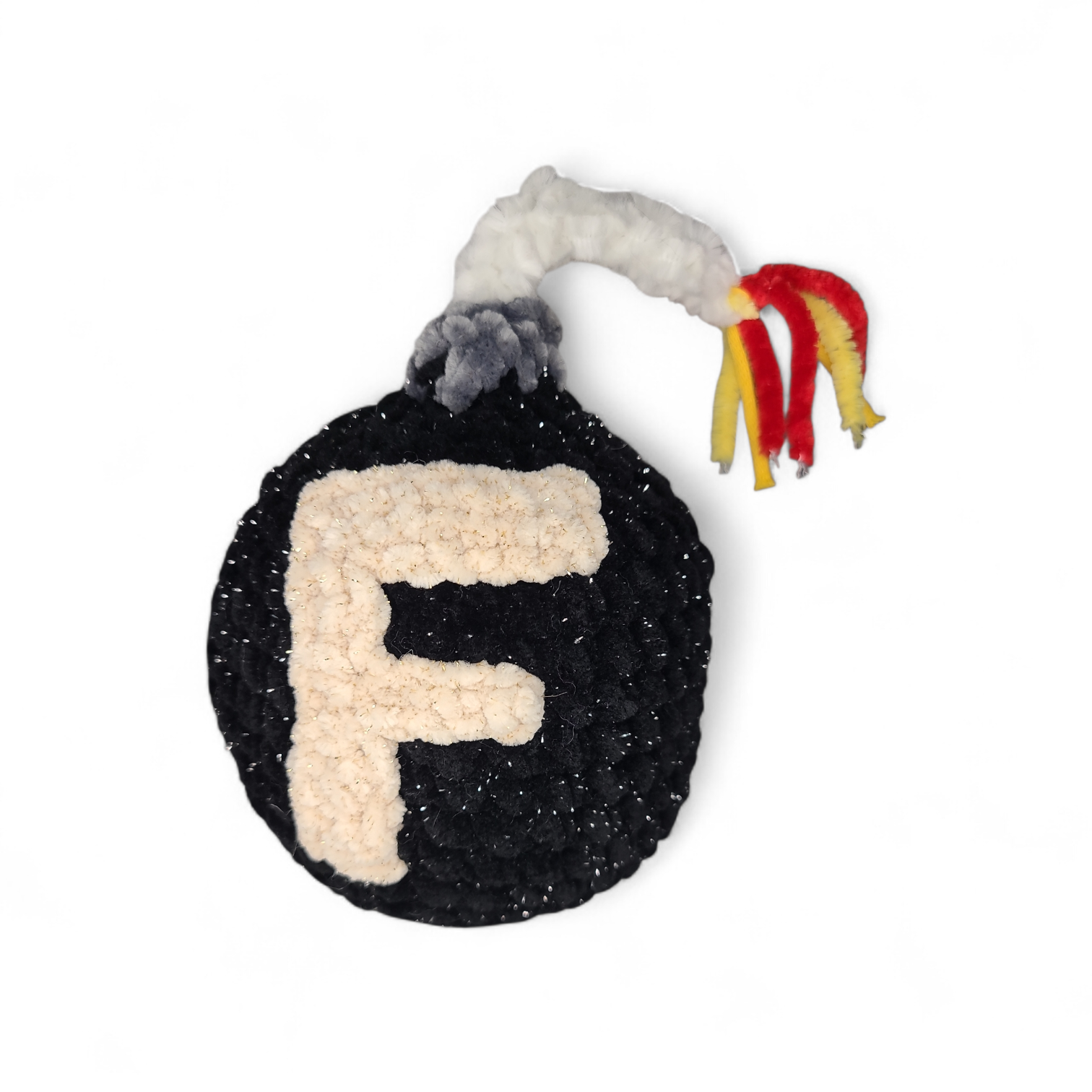 Crocheted plushie resembling a black bomb with a letter 'F' and colorful tail on a white background