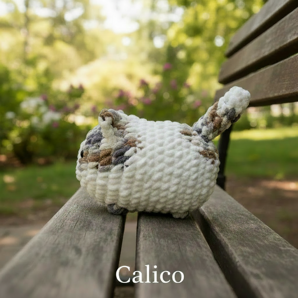 Crocheted calico loaf cat on a white background