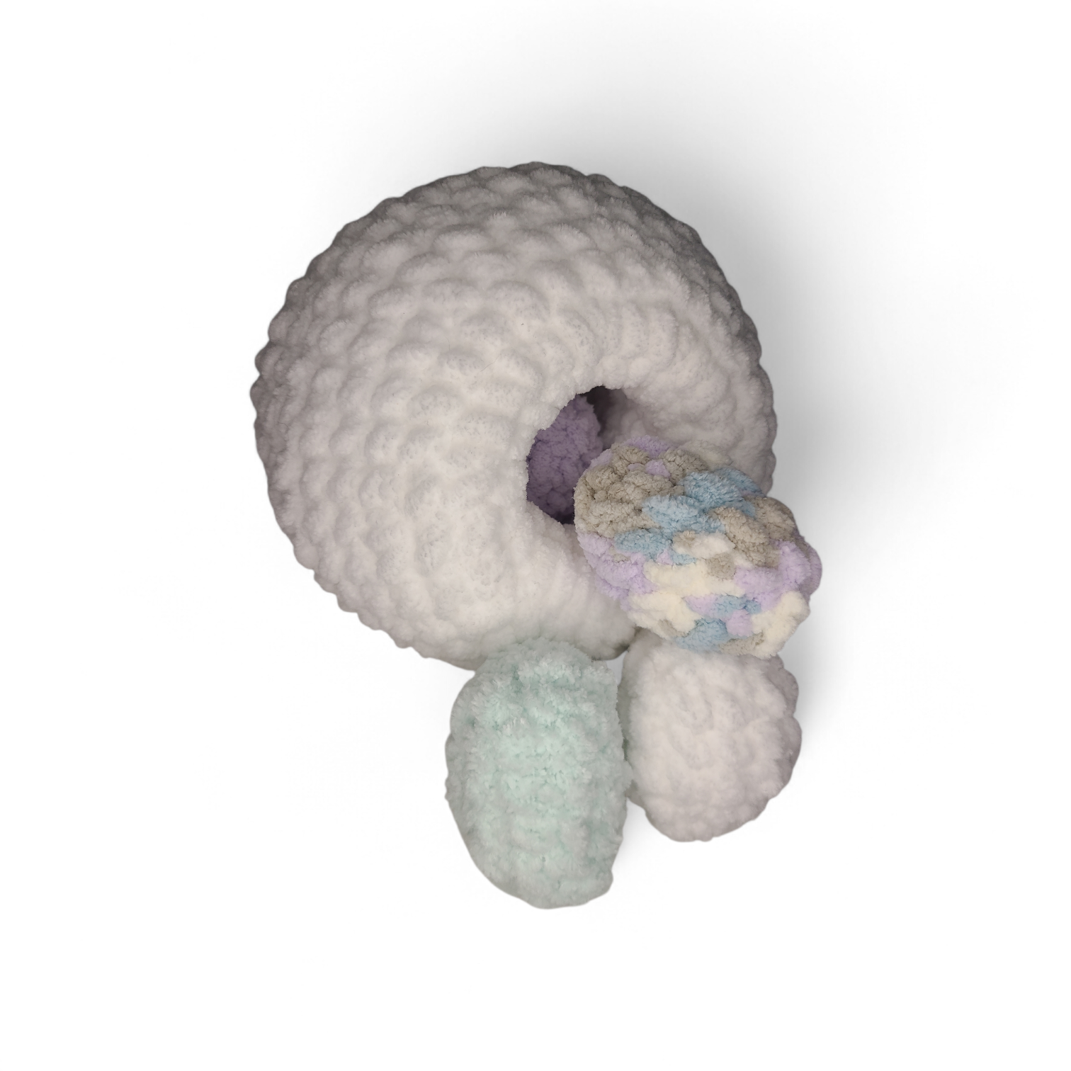 Bottom of a white Crocheted chicken with hole to hide eggs in on a light background