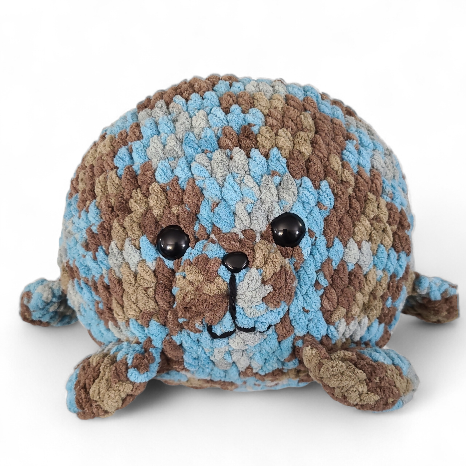 Crocheted seal plush toy with brown, blue, and beige pattern on a white background